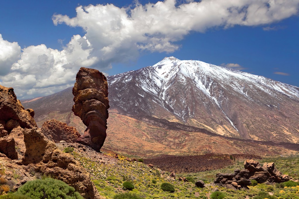 Besneeuwde top van de Teide op Tenerife met vulkanisch landschap en rotsformaties op de voorgrond.