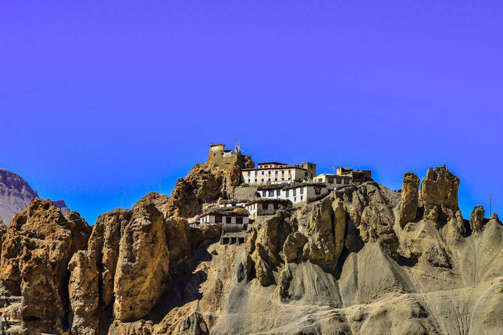 Boeddhistisch klooster op rotsachtige heuvel in Ladakh, India, onder heldere blauwe lucht.