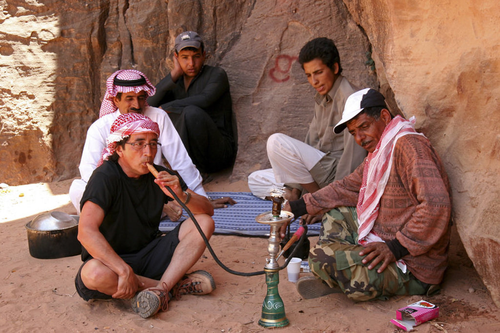 Reizigers roken waterpijp in een rotsachtige kloof tijdens een groepsrondreis door Jordanië.