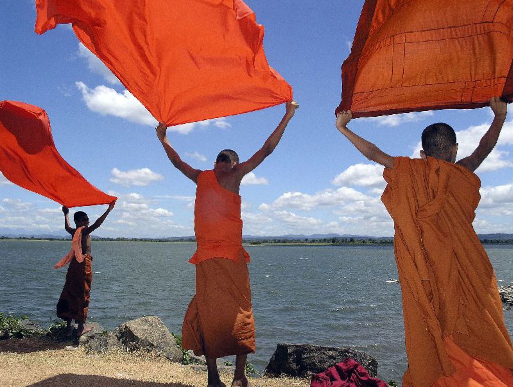 Boeddhistische monniken met oranje doeken aan een meer in Sri Lanka tijdens de groepsrondreis Hoogtepunten.