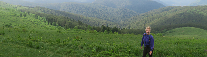 Wandelaar op een bergweide met uitzicht op groene bergen in Montenegro.
