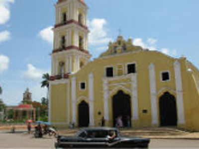 Iglesia Parroquial Mayor in Trinidad, Cuba, met klokkentoren en klassieke auto op straat.
