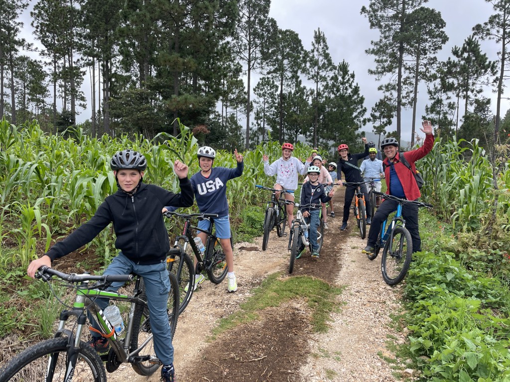 Gezin fietst over een onverhard pad langs maïsvelden tijdens een familiereis in Mexico.