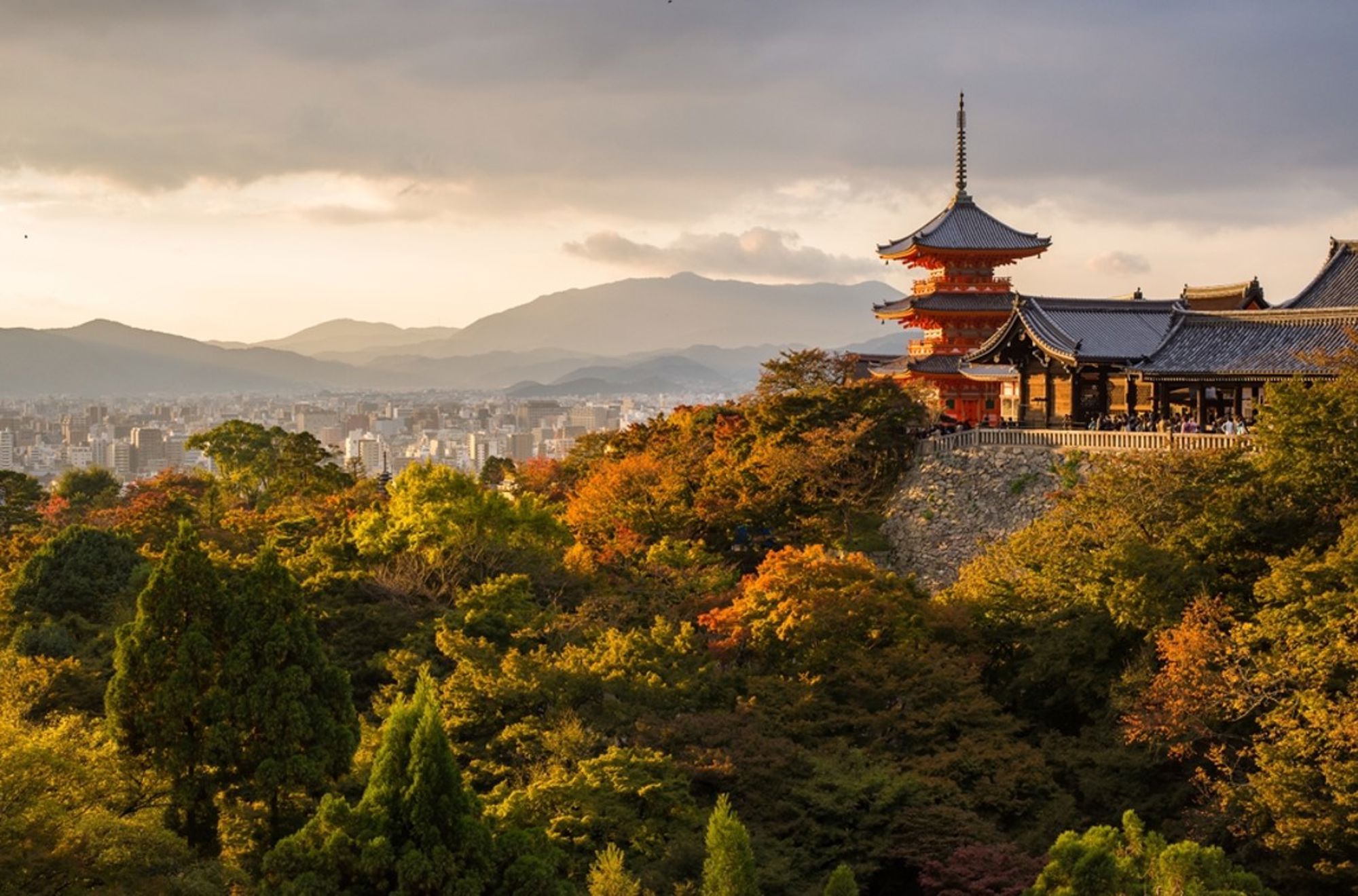Kiyomizu-dera tempel in Kyoto met uitzicht over de stad en herfstkleuren bij zonsondergang.