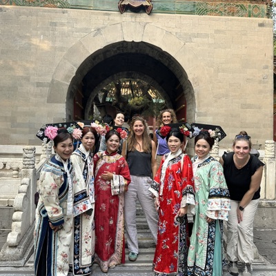 Groep vrouwen in traditionele Chinese kleding bij een tempelpoort tijdens een familiereis China.