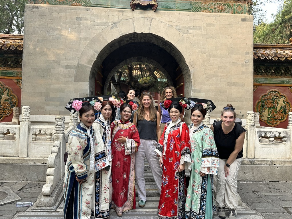 Groep vrouwen in traditionele Chinese kleding bij een tempelpoort tijdens een familiereis China.
