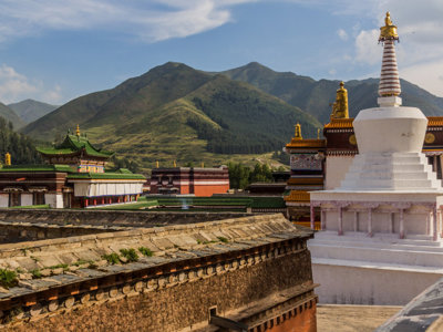 Boeddhistisch kloostercomplex met witte stupa en groene daken in berglandschap langs de Zijderoute.