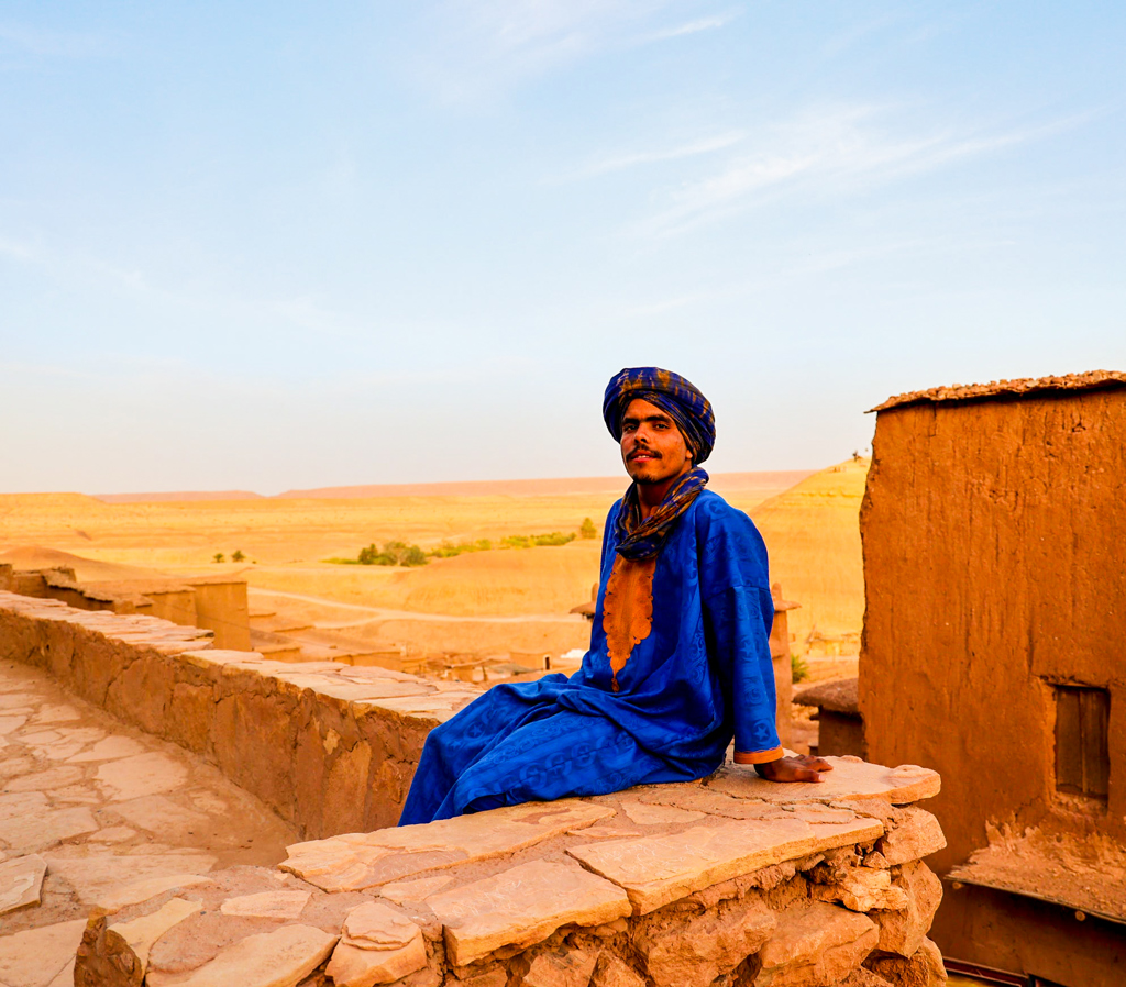 Man in traditionele kleding bij een kasbah in de woestijn van Marokko tijdens familiereis Marokko hoogtepunten.