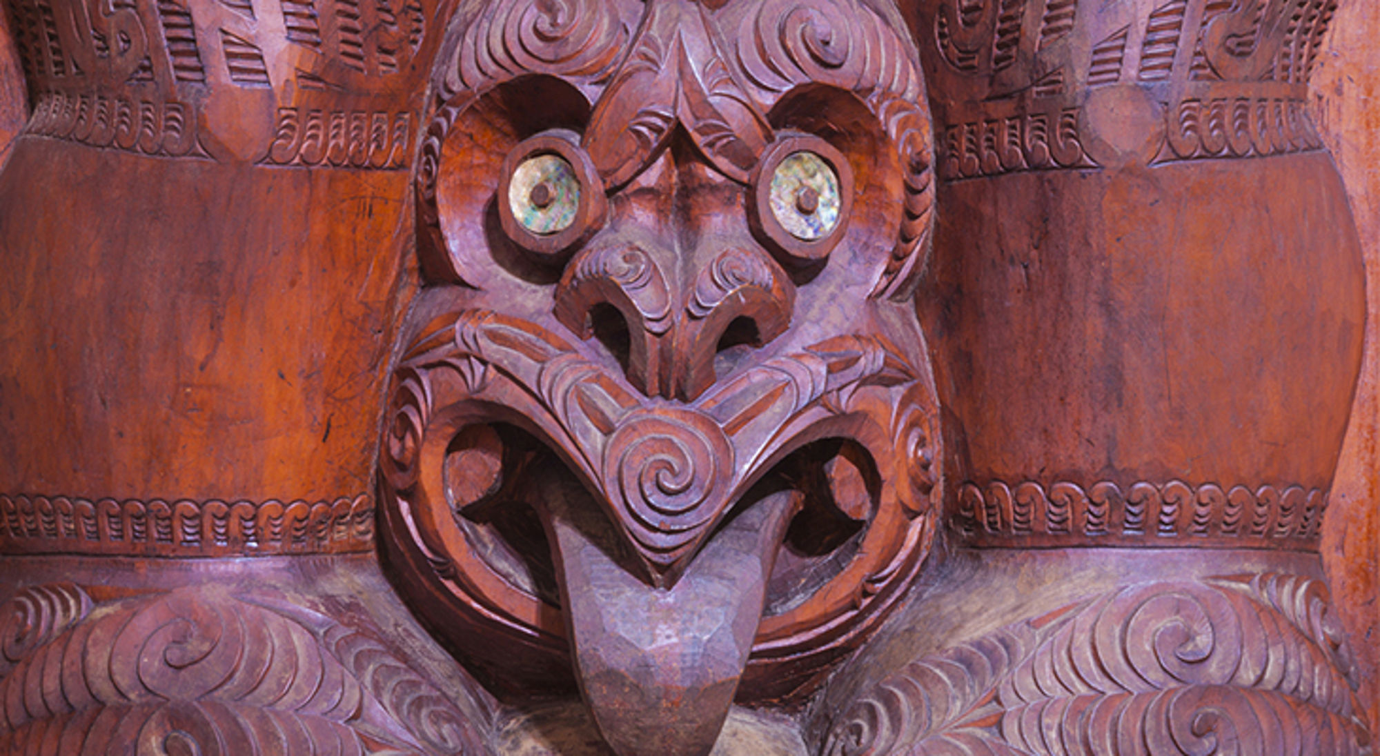 Maori in Nieuw-Zeeland Detail van een traditioneel houtsnijwerk met gezicht en ingelegde ogen.