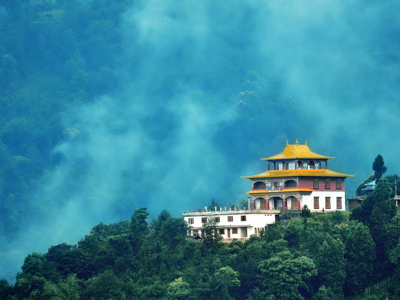 Boeddhistisch klooster met gouden dak op een groene berghelling in de mist, route Sikkim en Bhutan.