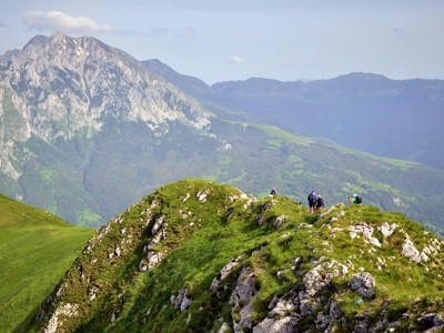 Wandelaars op een groene bergkam met uitzicht op ruige bergen in Bosnië & Herzegovina.
