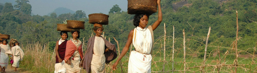 Vrouwen in Orissa, India lopen met manden op het hoofd door het groene heuvellandschap.