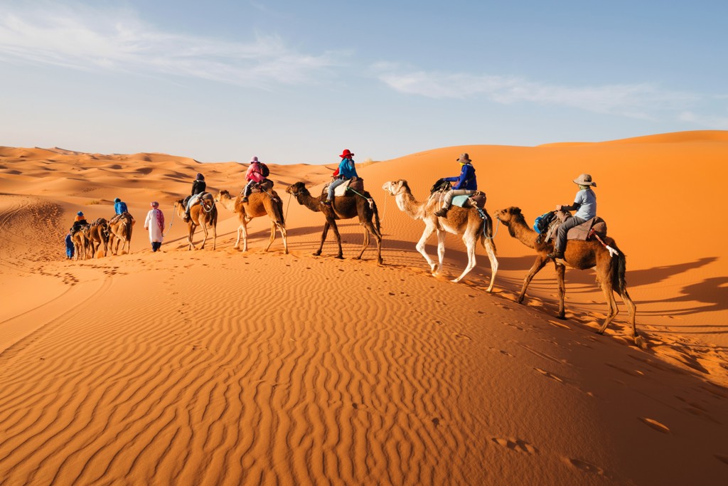 Familie op kamelentocht door de zandduinen van de Sahara in Marokko tijdens de zomerreis.