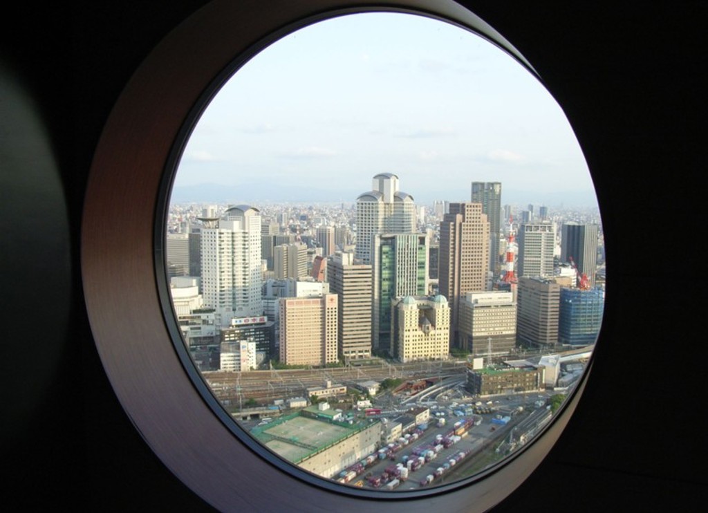 Uitzicht op de skyline van Osaka door een rond raam tijdens een familiereis Japan.