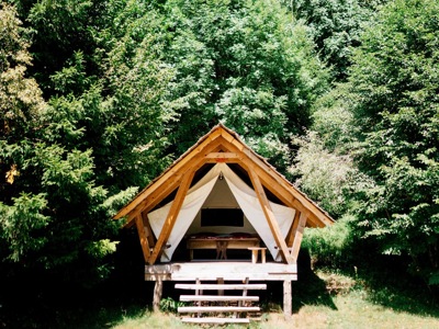 Glamping-tent op houten platform in het groene bos tijdens de Route Slovenië.