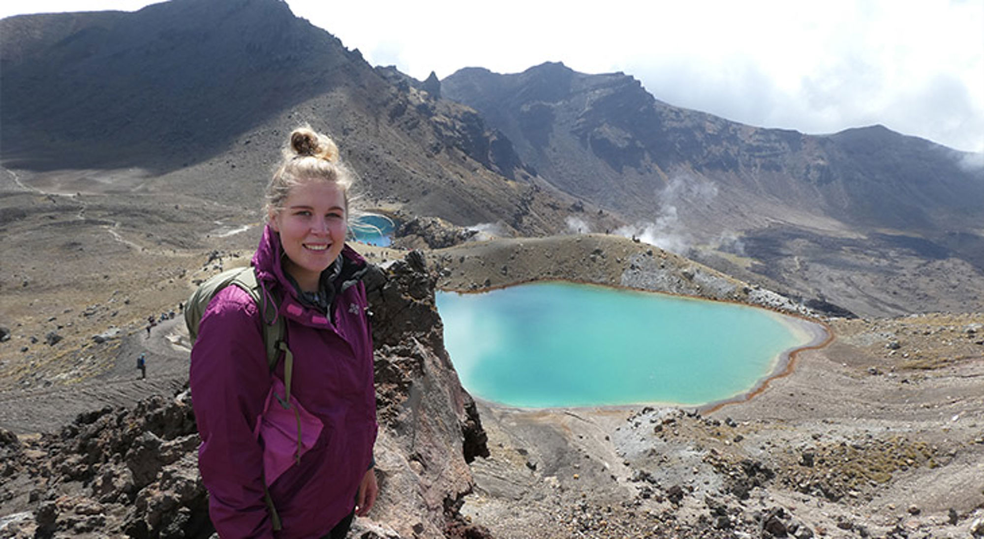 Emerald Lakes Vrouw met rugzak bij felblauw kratermeer in vulkanisch berglandschap.