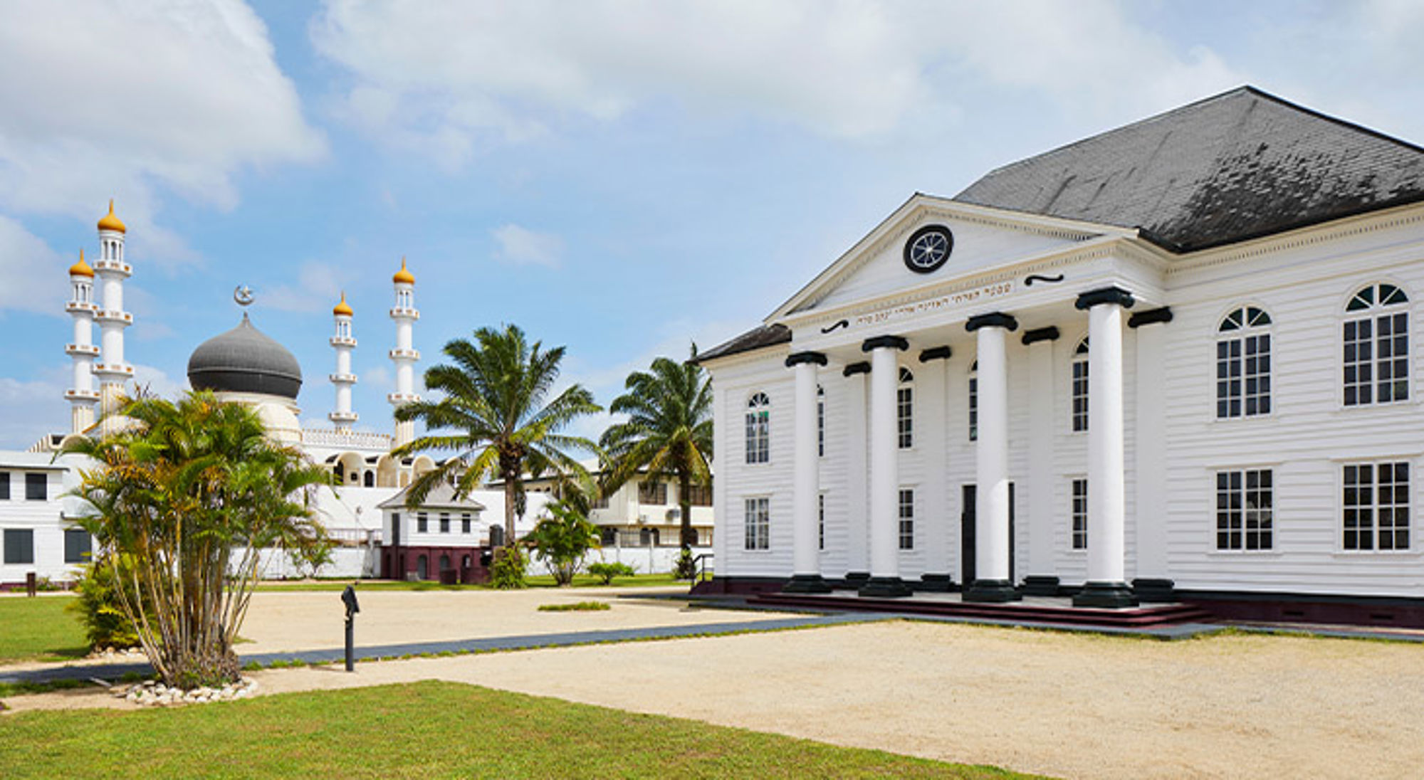 Moskee en synagoge Keizerstraat Paramaribo Witte houten koloniale gebouwen met zuilen en moskee met minaretten en koepel in Paramaribo, Suriname.