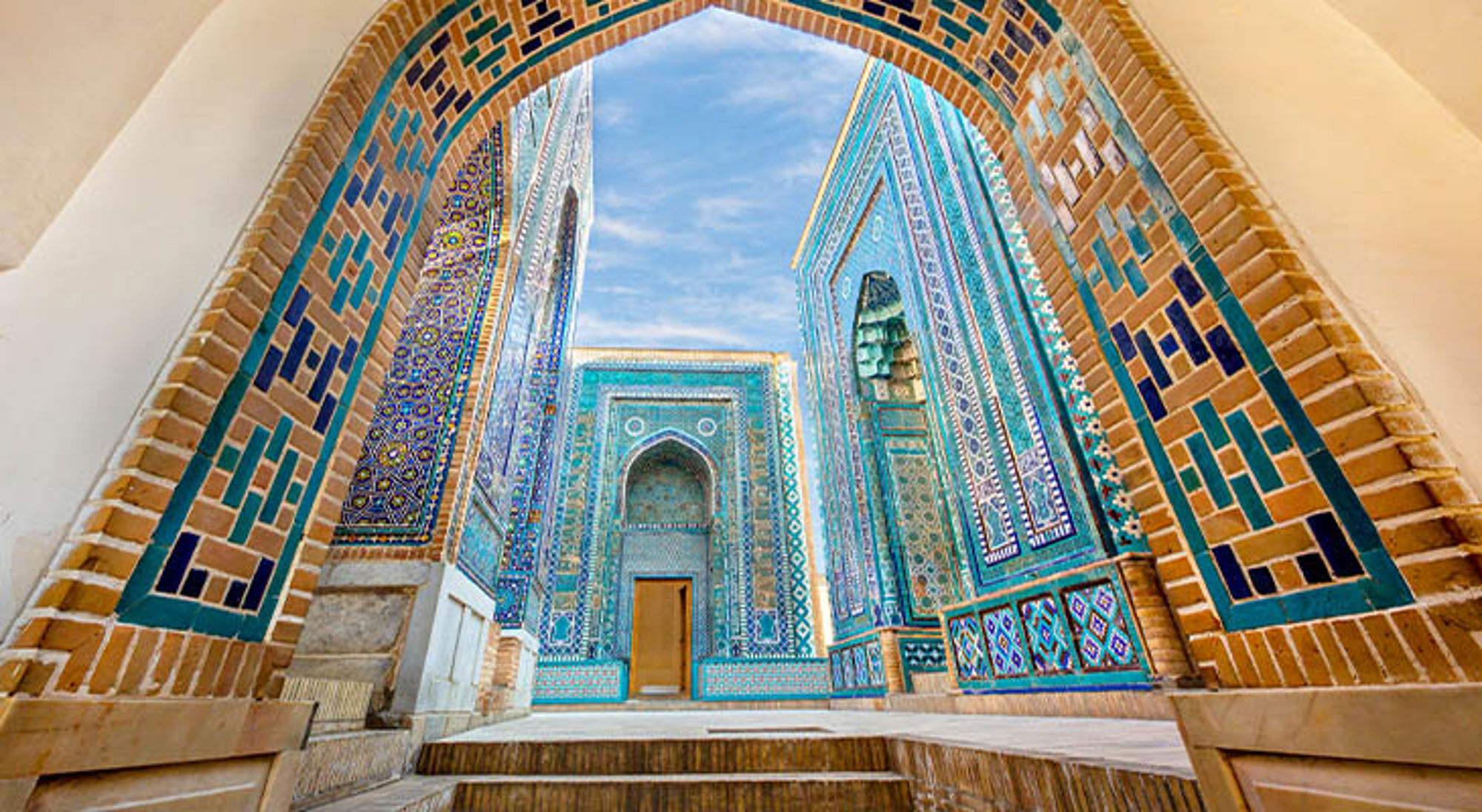 Blauwe mozaïekgevels en tegelbogen van een historische madrassa in Samarkand.