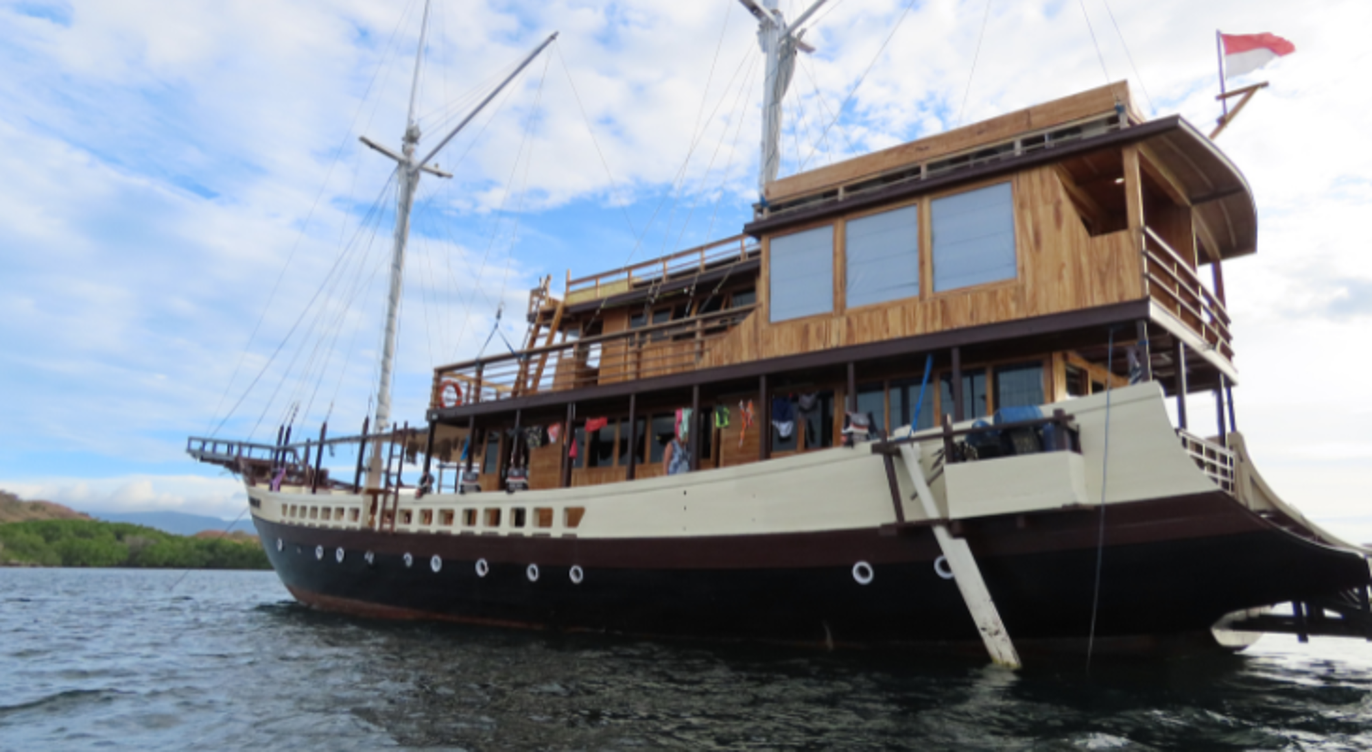 Traditionele houten boot voor een meerdaagse cruise op zee, met blauwe lucht op de achtergrond.