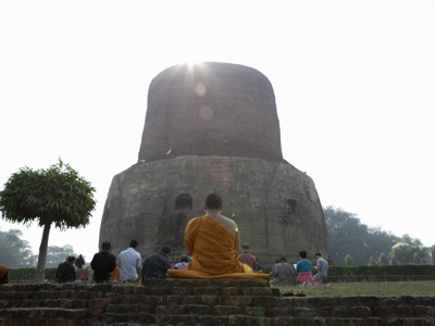Monnik mediteert voor de Dhamek Stupa in Sarnath tijdens de route India en Nepal, 21 dagen.