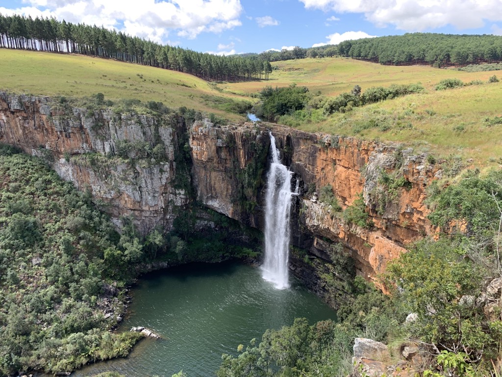 Waterval in een diepe kloof met groene heuvels tijdens een 22-35ers reis door Zuid-Afrika.