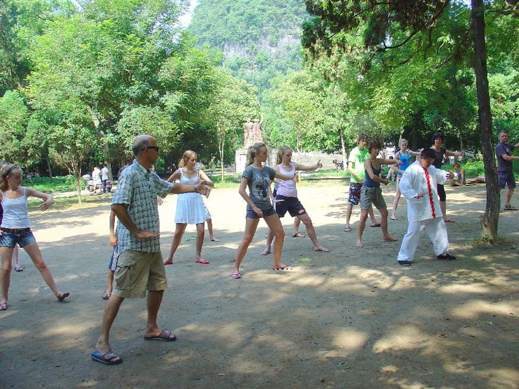 Tai chi-les in een park tijdens een familiereis China, met deelnemers die de bewegingen nadoen.