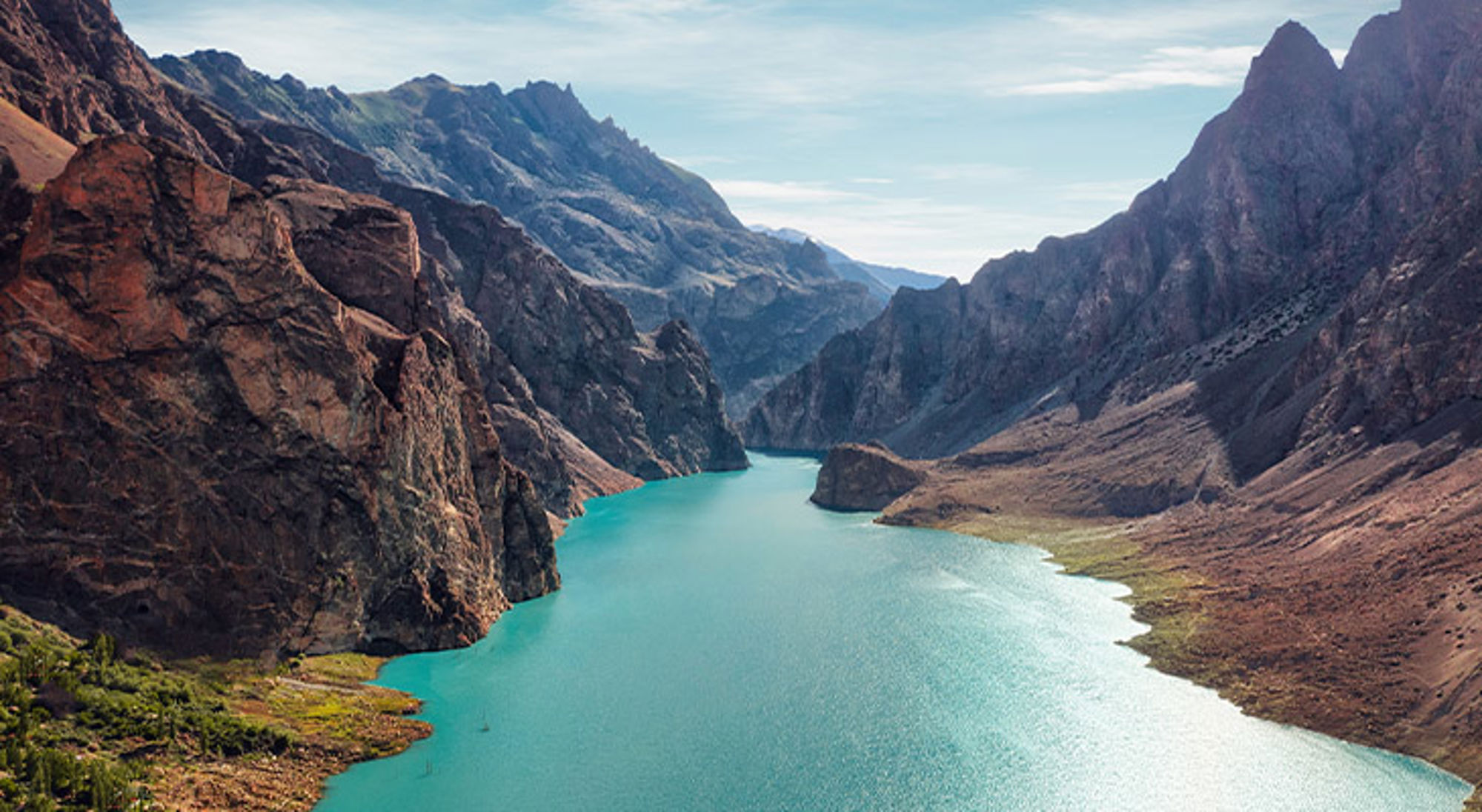 Attabad Meer Pakistan Turquoise bergmeer tussen ruige rotswanden en hoge bergtoppen onder een heldere lucht.