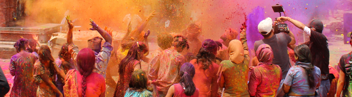 Festivalvierders gooien kleurrijk poeder in de lucht tijdens Holi in Nepal.