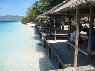 Strandpaviljoens aan het witte zandstrand van Gili Air met helderblauw zeewater.