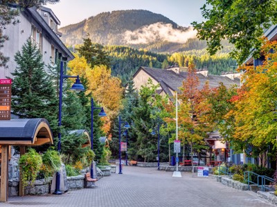 Straat in Whistler Village met kleurrijke herfstbomen en bergen op de achtergrond, Route Canada.