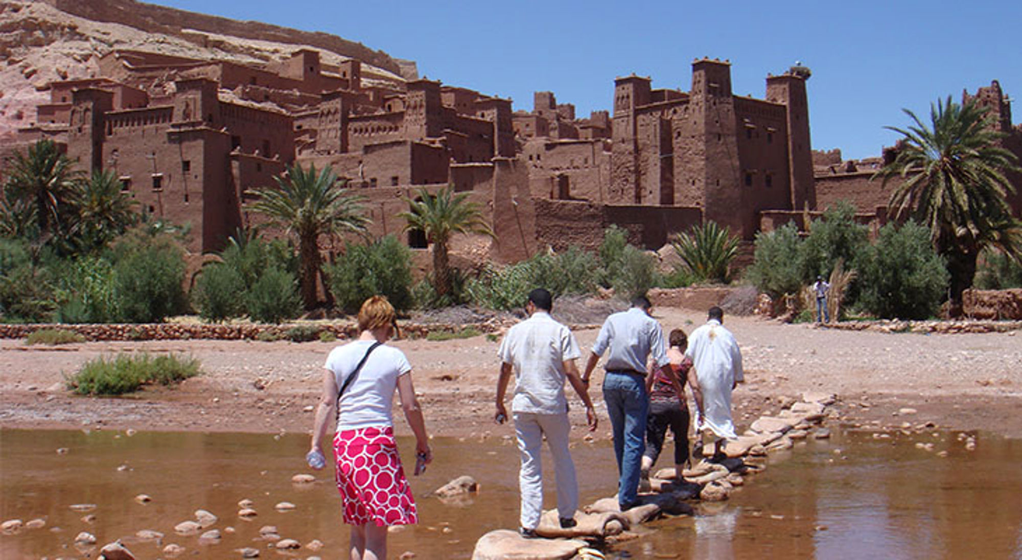 Aït Ben Haddou Toeristen steken een rivier over naar de kasbah van Aït Ben Haddou in Marokko.
