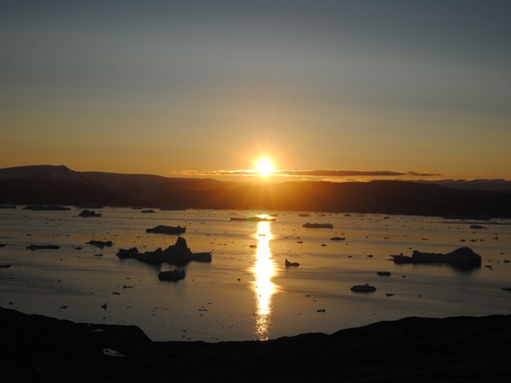 Zonsondergang boven een Groenlandse fjord met drijvende ijsbergen tijdens de groepsrondreis Groenland Expeditie.