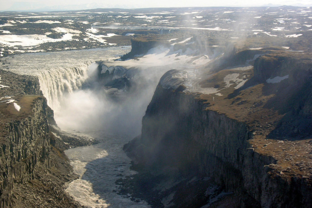 Waterval Dettifoss in IJsland stort in een diepe kloof, met nevel boven het ruige landschap.