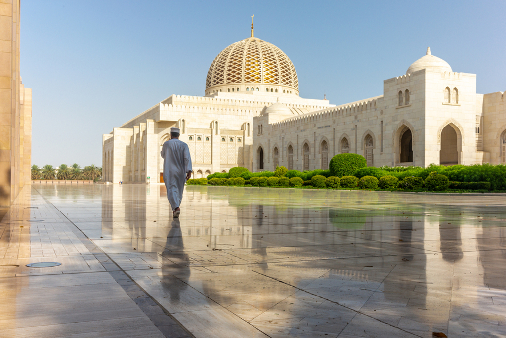 Man loopt over binnenplein bij de Sultan Qaboos Grand Mosque in Muscat, Oman.