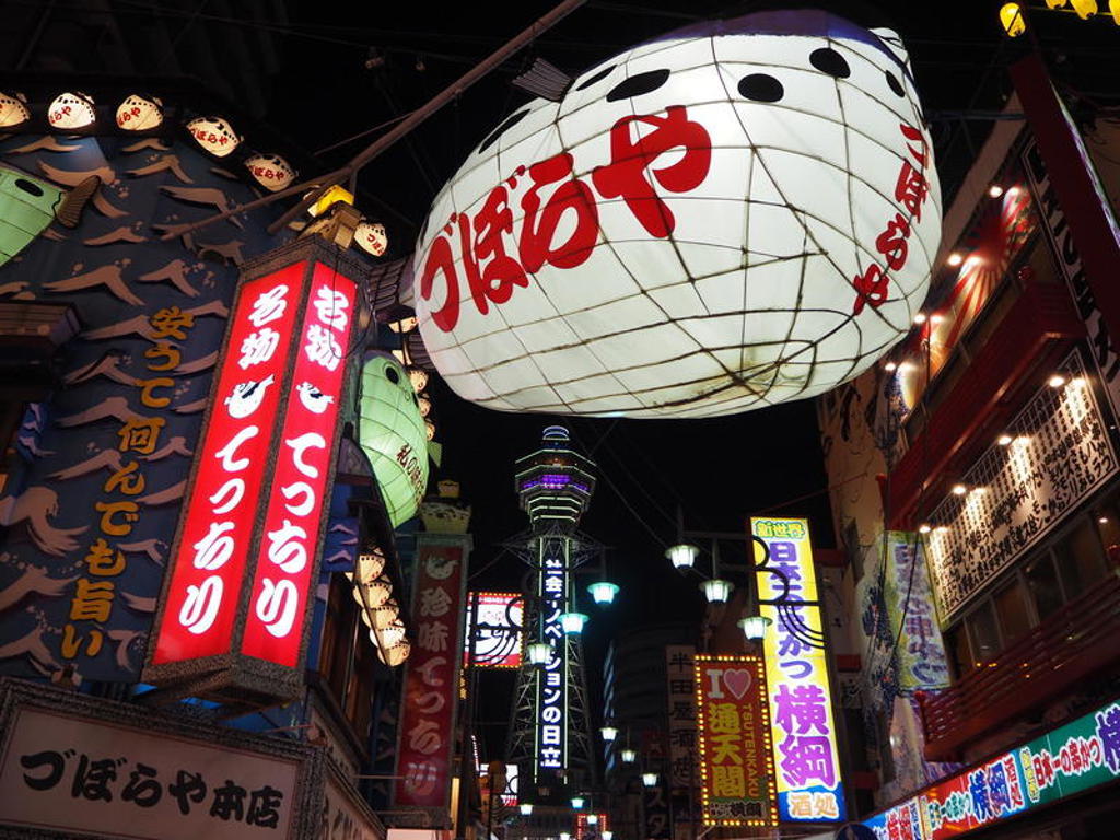 Verlichte neonreclames en lantaarns in een Japanse straat bij avond, tijdens een groepsrondreis Japan.
