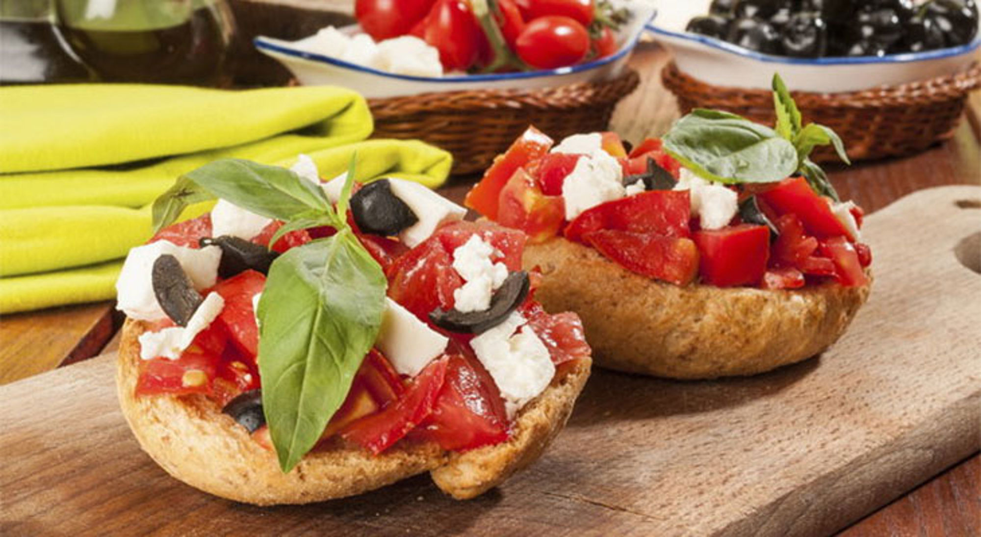 Italiaans eten Bruschetta met tomaat, feta, zwarte olijven en basilicum op een houten plank.