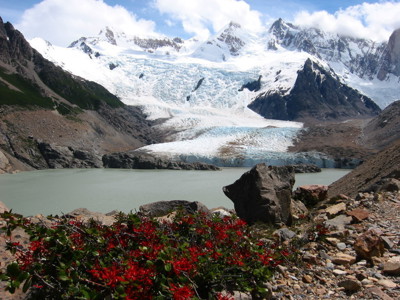 Uitzicht op een gletsjer die uitmondt in een bergmeer, omringd door besneeuwde pieken in Patagonië.