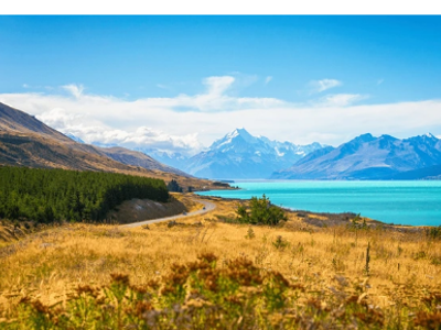 Panoramisch uitzicht op Lake Pukaki met turquoise water, bergen en kronkelende weg op het Zuidereiland van Nieuw-Zeeland.