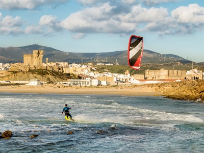Kitesurfer voor het strand van Tarifa met uitzicht op het oude kasteel en de stad, Andalusië.