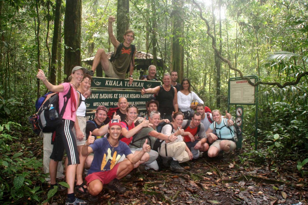 Groepsreizigers bij het bord van Gunung Mulu National Park in het regenwoud van Maleisisch Borneo.