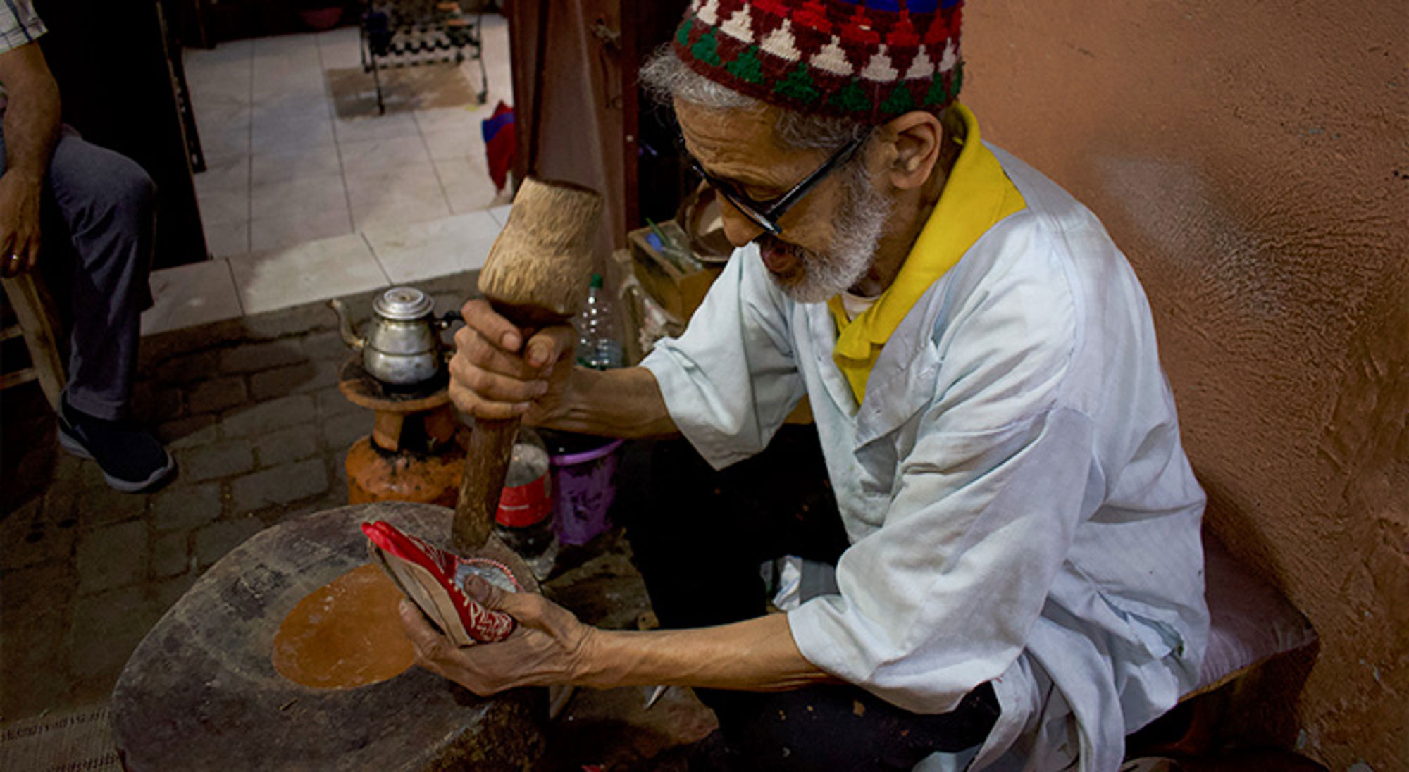 Leerbewerken Marrakech Schoenmaker repareert een rode schoen met hamer in een werkplaats.