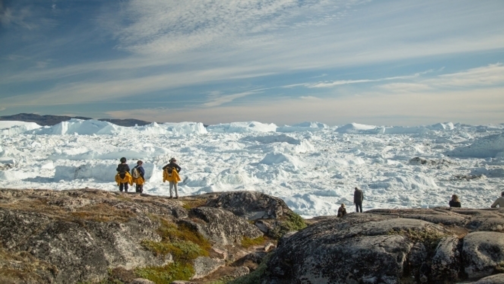 Reizigers kijken uit over een uitgestrekt ijslandschap in Arctisch Canada en Groenland tijdens de Northwest Passage-cruise.
