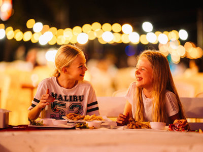 Kinderen eten en lachen bij een avondmarkt in Thailand tijdens de familiereis Thailand Hoogtepunten.