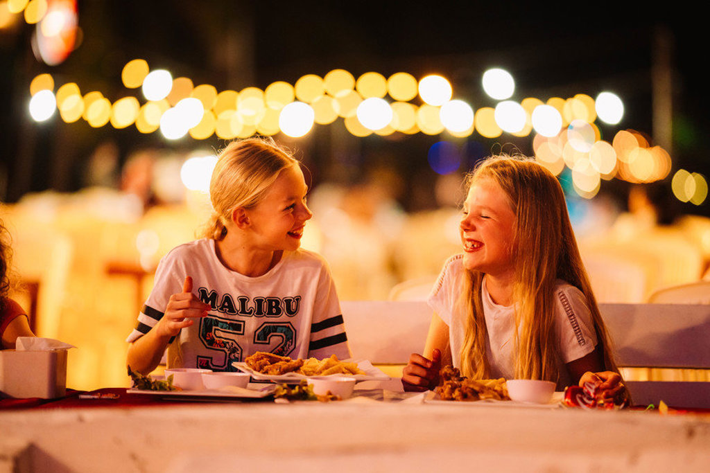 Kinderen eten en lachen bij een avondmarkt in Thailand tijdens de familiereis Thailand Hoogtepunten.