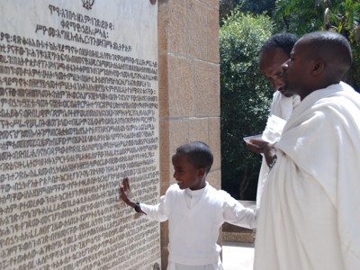Ethiopisch-orthodoxe gelovigen lezen Ge’ez-inscripties bij een kerk tijdens de route Ethiopië van 29 dagen.