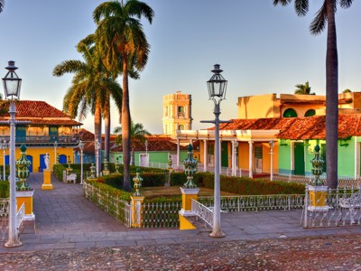 Kleurrijke gebouwen en palmbomen op Plaza Mayor in Trinidad, Cuba.