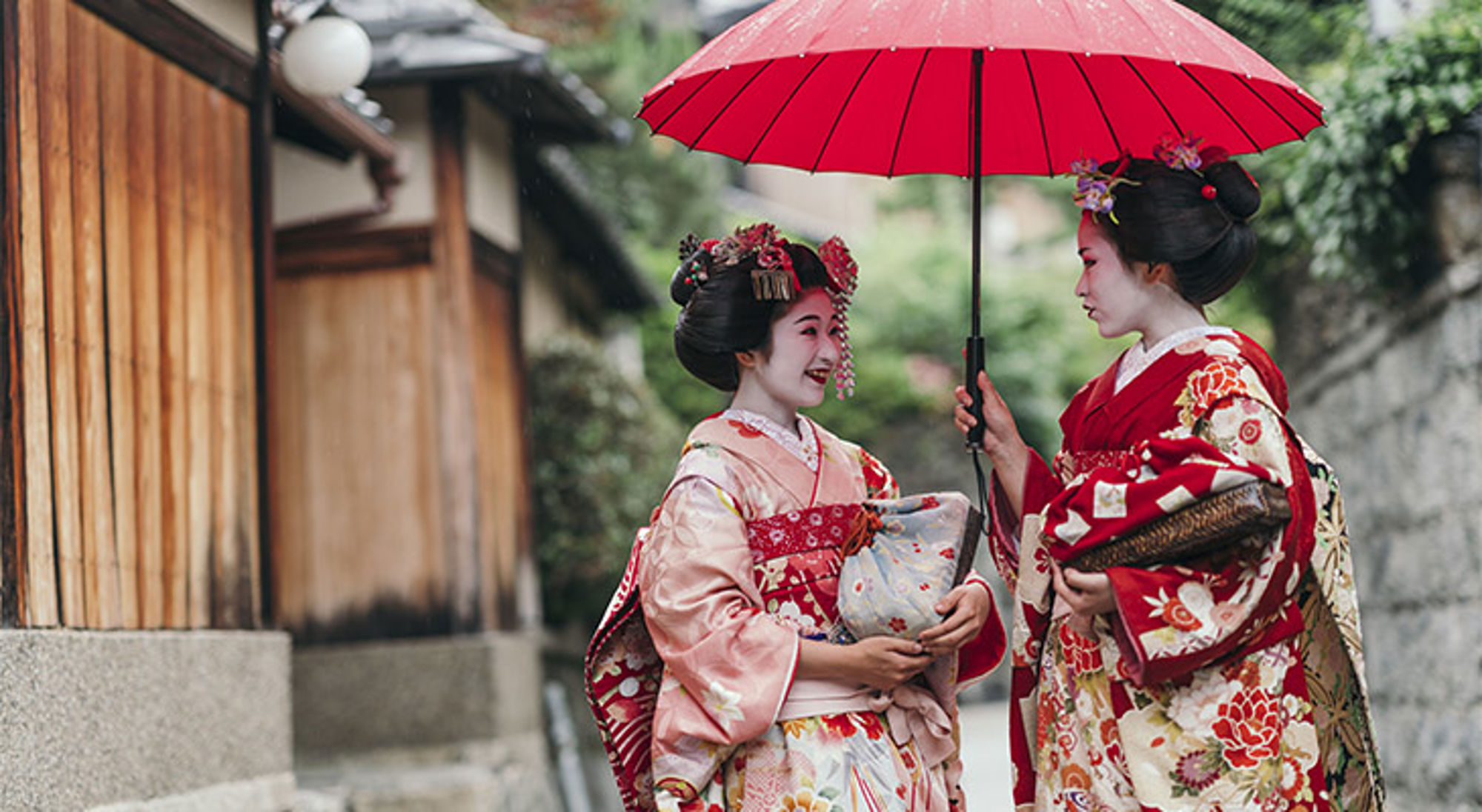 Kyoto geisha's Twee vrouwen in kimono met rode paraplu in een Japanse straat.